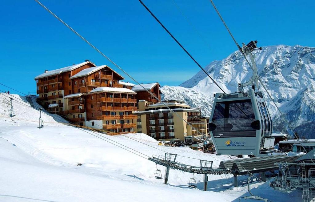 une remontée mécanique avec un bâtiment dans la neige dans l'établissement Appartement 6 places aux pieds des pistes avec piscine, wifi et parking privé, salle de bain refaite à neuf, à Orcières