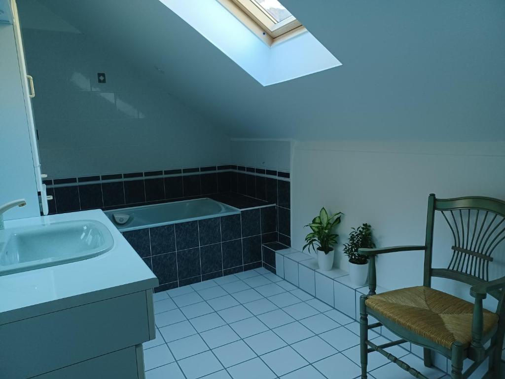 a bathroom with a tub and a chair and a sink at La Grange de Lily in Vic-sur-Cère