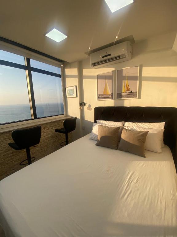 - une chambre avec un grand lit blanc et une grande fenêtre dans l'établissement VITORIA MARINA Flat CORREDOR DA VITORIA, à Salvador