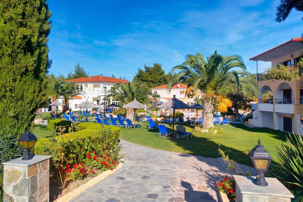 a resort with a lawn with chairs and umbrellas at Chrousso Village in Paliouri