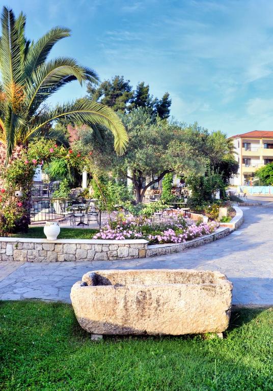 a stone bench sitting in the grass in a park at Chrousso Village in Paliouri
