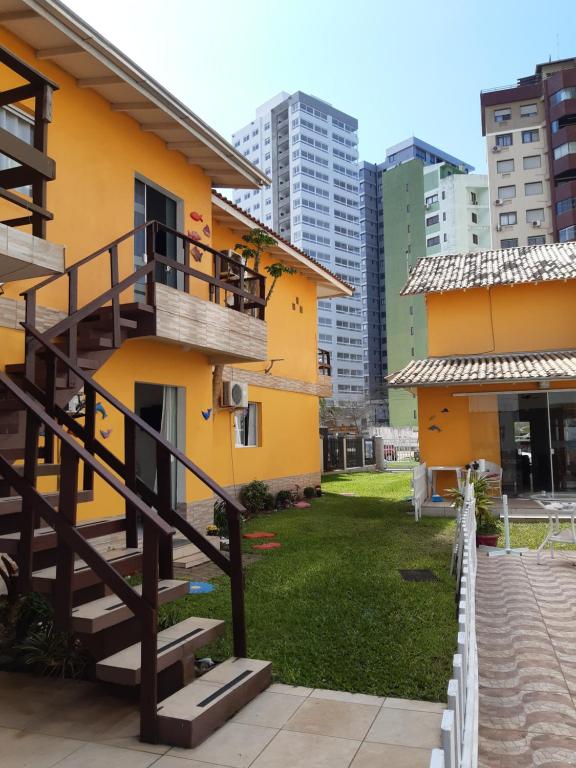 una casa amarilla con una escalera junto a un patio en Cozinha Equipada em Apartamento para Alugar em Torres RS, en Torres