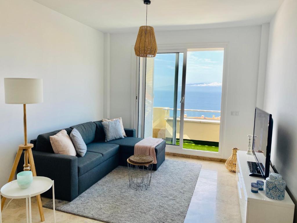 - un salon avec un canapé bleu et une vue sur l'océan dans l'établissement Los Gigantes Ocean View Apartment, à Puerto de Santiago