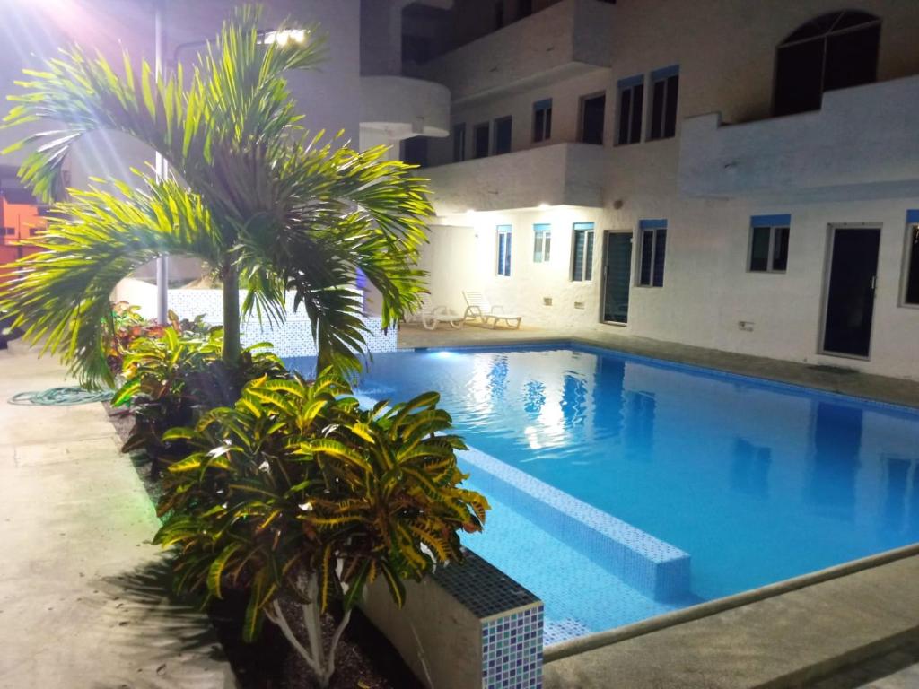 a swimming pool with palm trees in front of a building at Departamento Tonsupa, Conjunto Santorini Blue in Tonsupa