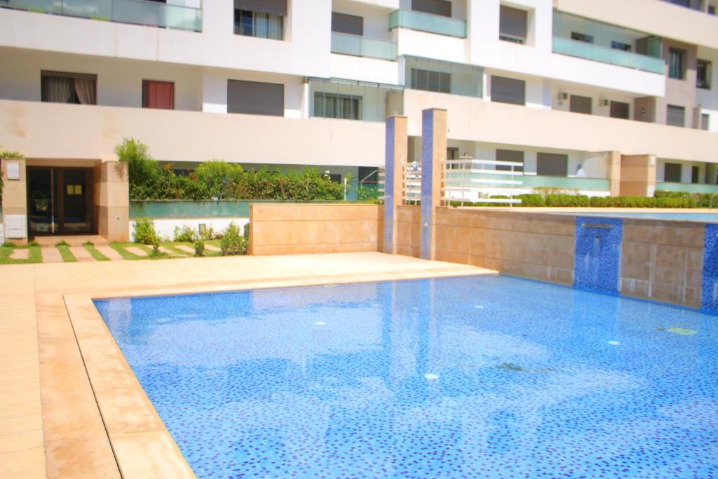 a swimming pool in front of a building at Appartement dans résidence Paradis Beach in Mohammedia