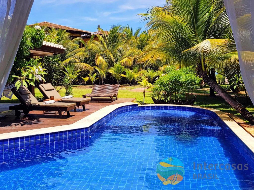 una piscina frente a un complejo con palmeras en Villa Bora Bora - Frente mar, Praia do Forte, en Praia do Forte