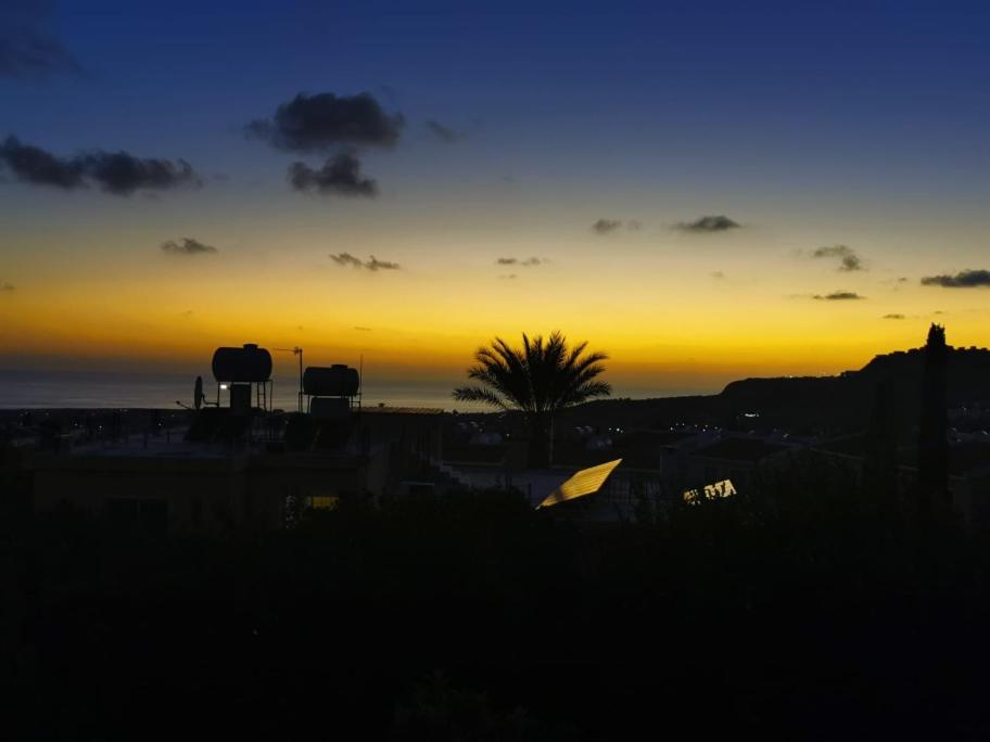 einen Sonnenuntergang mit einer Palme und einem Zelt auf einem Feld in der Unterkunft Peyia Sunset in Peyia