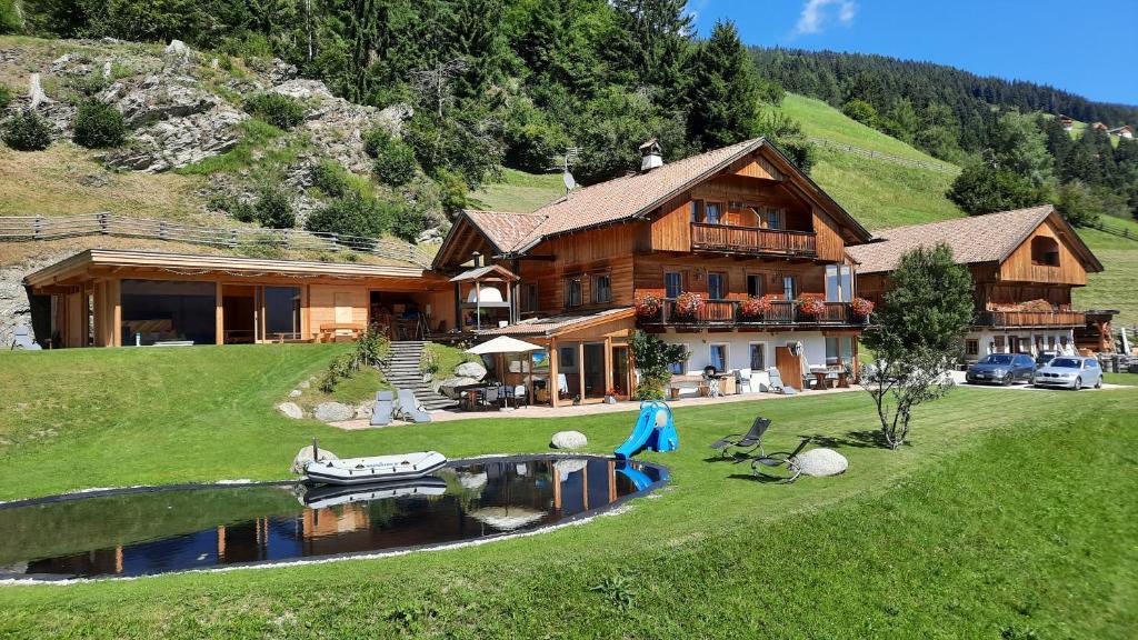 a large wooden house with a boat in the water at Apartment Himmelreichhof in San Candido