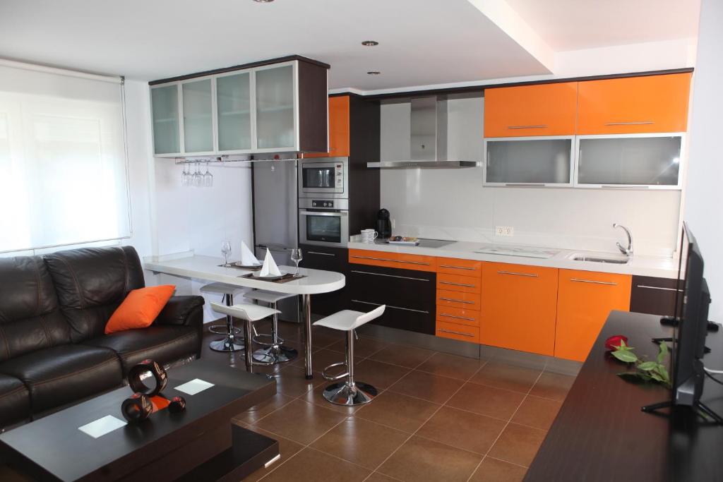 uma sala de estar com um sofá e uma cozinha com armários laranja em Apartamento Los Canarios em Corcubión