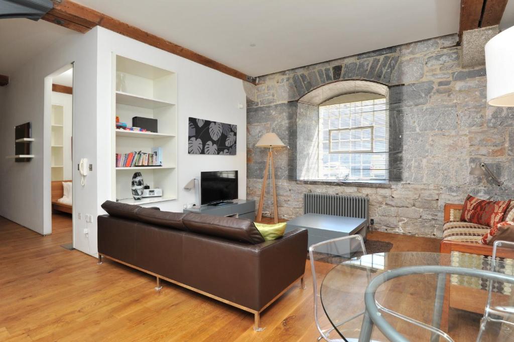 a living room with a leather couch and a stone wall at Drakes Wharf @ Royal William Yard in Plymouth