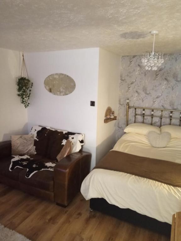 a bedroom with a bed and a leather couch at Havisham Studio Flat Rochester ME1 1XZ in Strood