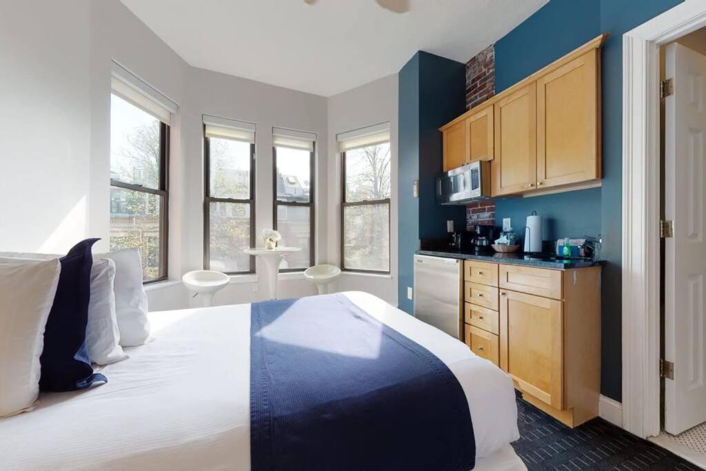 Cet appartement comprend une chambre dotée d'un grand lit, de murs bleus et de fenêtres. dans l'établissement Cozy Downtown Boston Studio, #45, à Boston