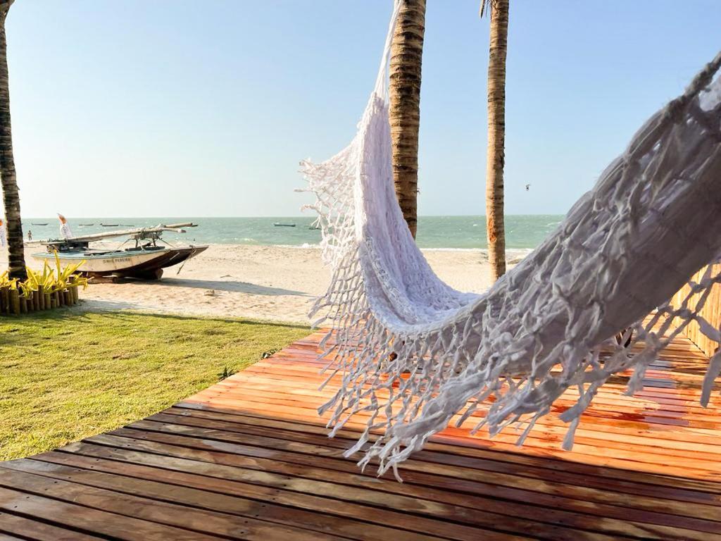 a hammock on a deck next to the beach at Casa ADOBE Preá - FRENTE MAR! in Prea