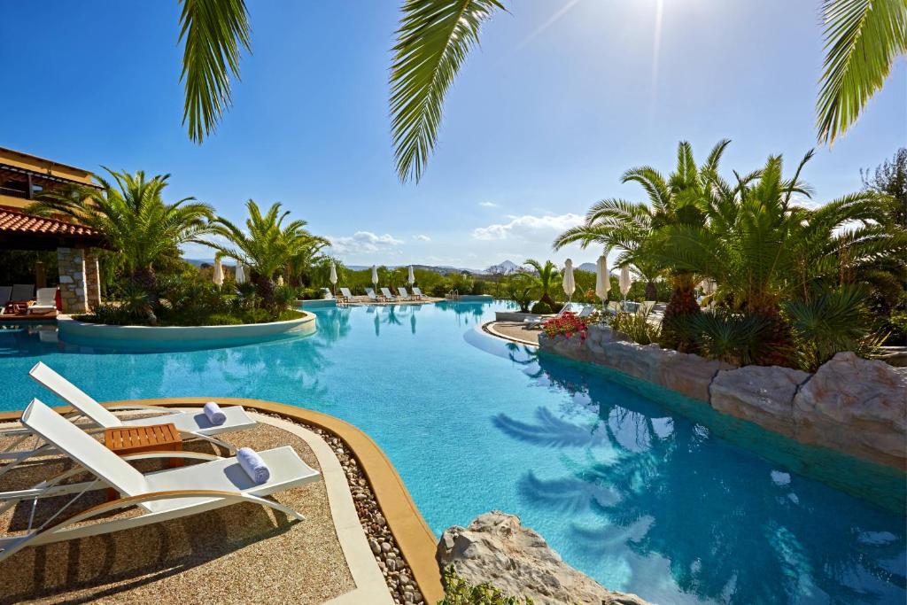 - une piscine dans un complexe avec des chaises et des palmiers dans l'établissement The Westin Resort, Costa Navarino, à Romanu