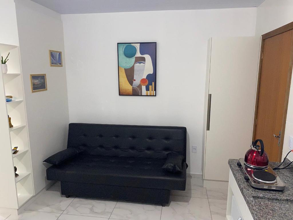a black couch in a living room with a painting at Residencial Campeche in Florianópolis