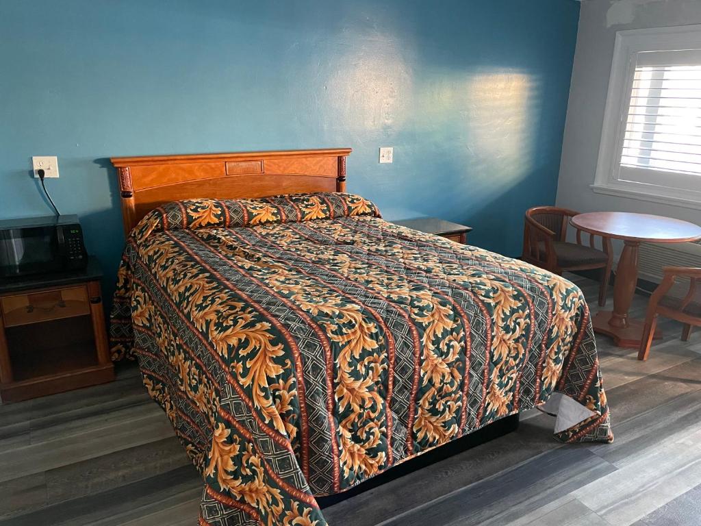 a bedroom with a bed with a colorful comforter at La Casa Motel, Garden Grove - Anaheim in Garden Grove