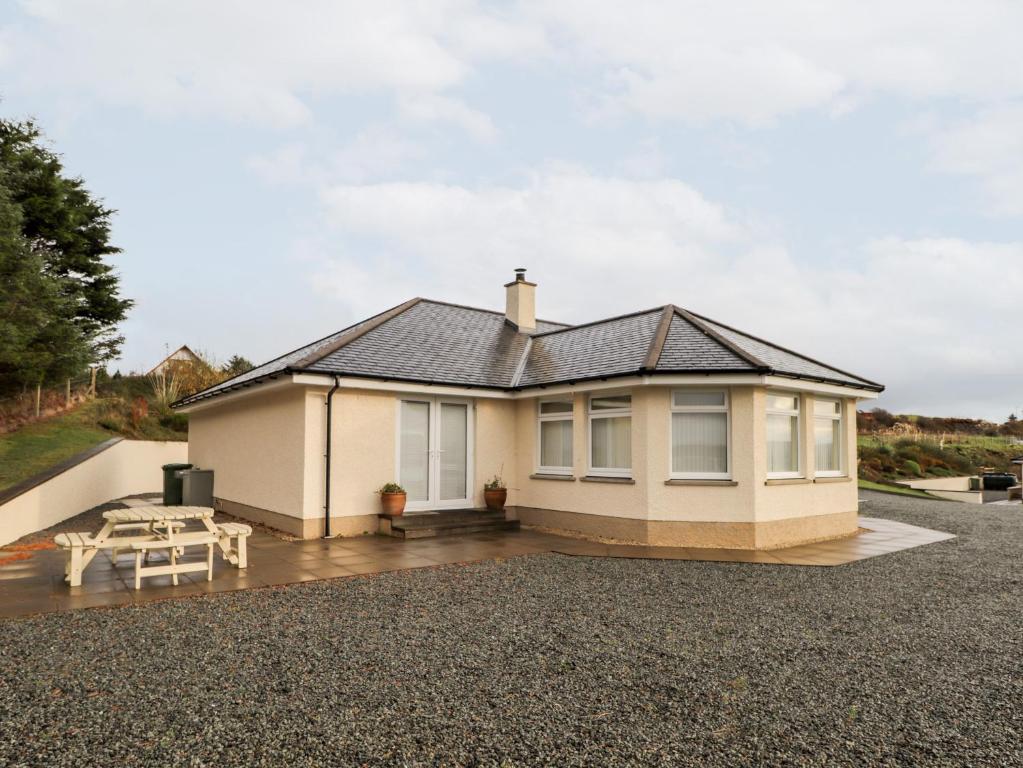 a detached house with a patio and a table at Riverside Cottage in Portree