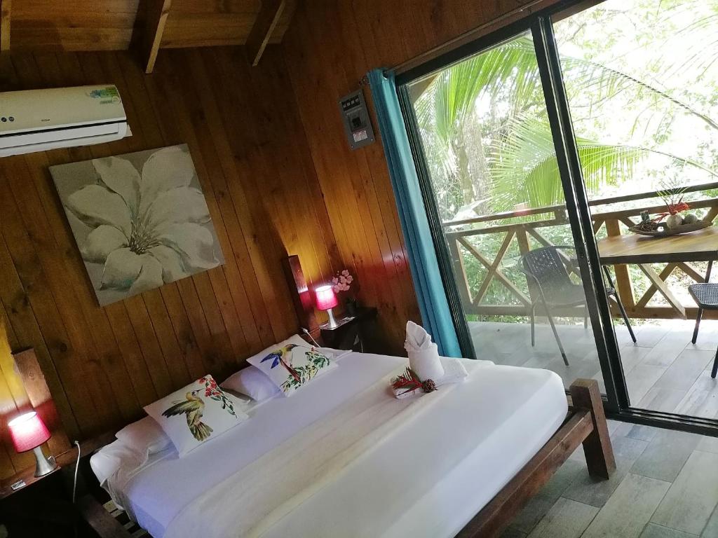 a bedroom with a large bed and a large window at Casa el Colibrí in Parrita