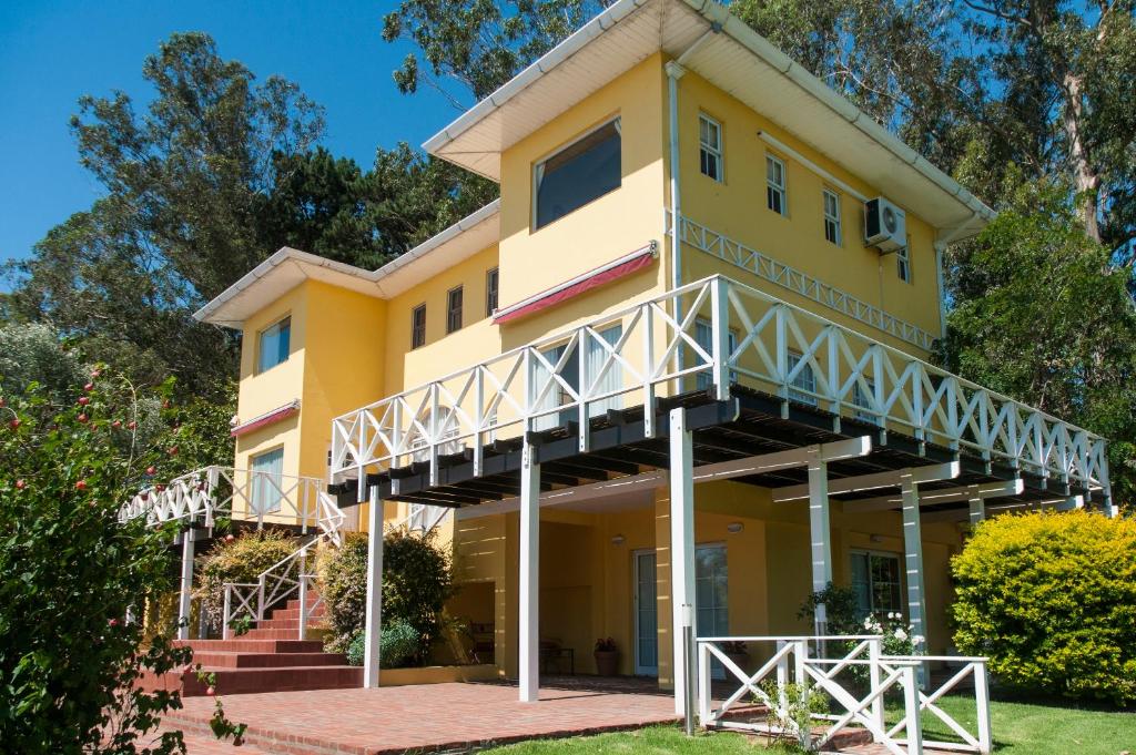 ein gelbes Haus mit einem Balkon und einer Treppe in der Unterkunft Valle Dorado Sierra de los Padres in Sierra de los Padres