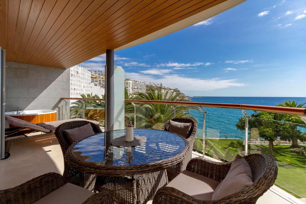 a balcony with a table and chairs and the ocean at Radisson Blu Resort Gran Canaria in La Playa de Arguineguín