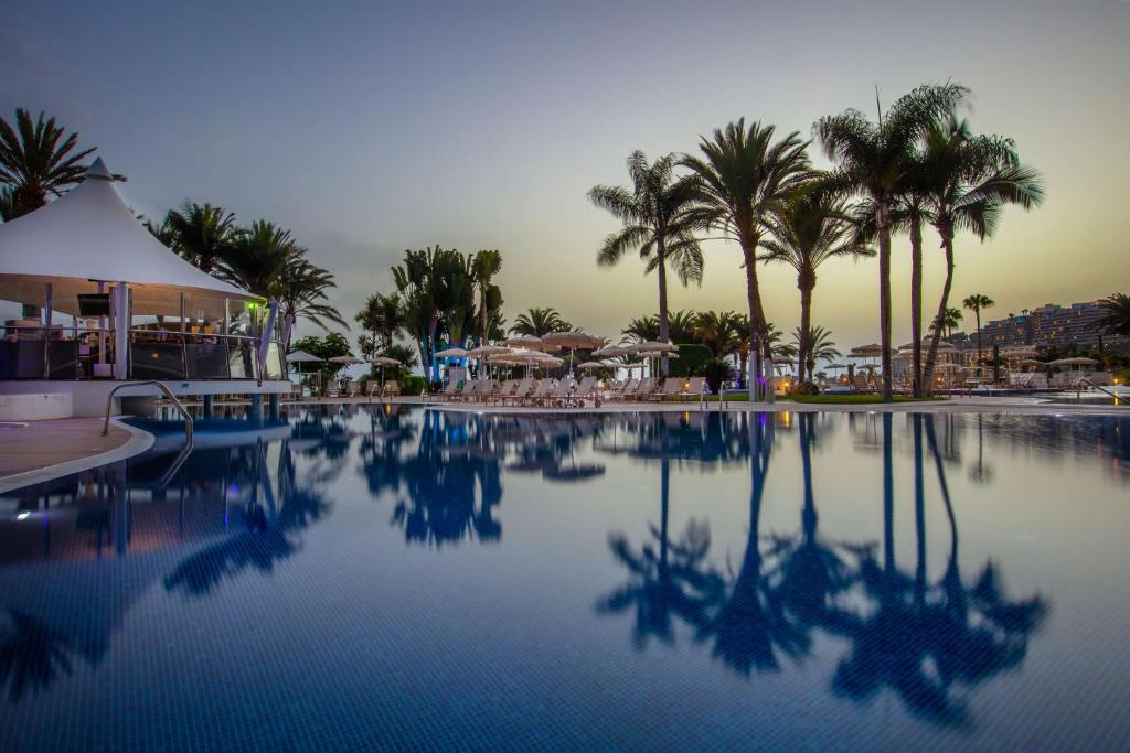 a swimming pool with palm trees and a resort at Radisson Blu Resort Gran Canaria in La Playa de Arguineguín