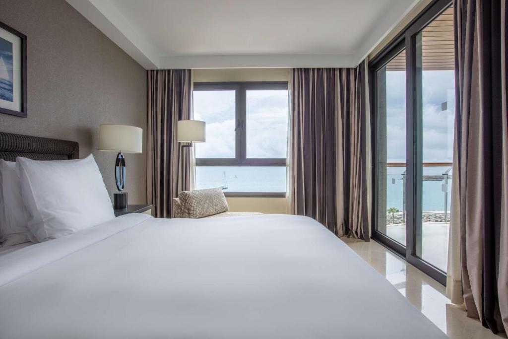 a bedroom with a large bed and a large window at Radisson Blu Resort Gran Canaria in La Playa de Arguineguín
