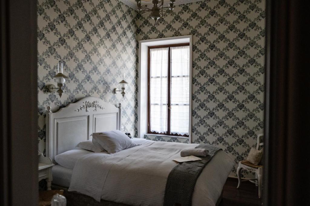 sypialnia z białym łóżkiem w pokoju z tapetą w obiekcie Boutique Hotel Anagennisis w mieście Pirgos