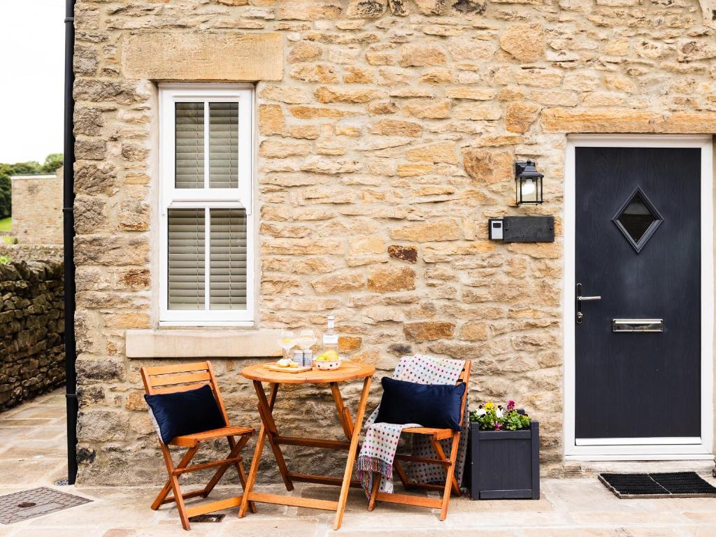 a patio with a table and chairs next to a stone building at Hush Cottage in Middleton in Teesdale