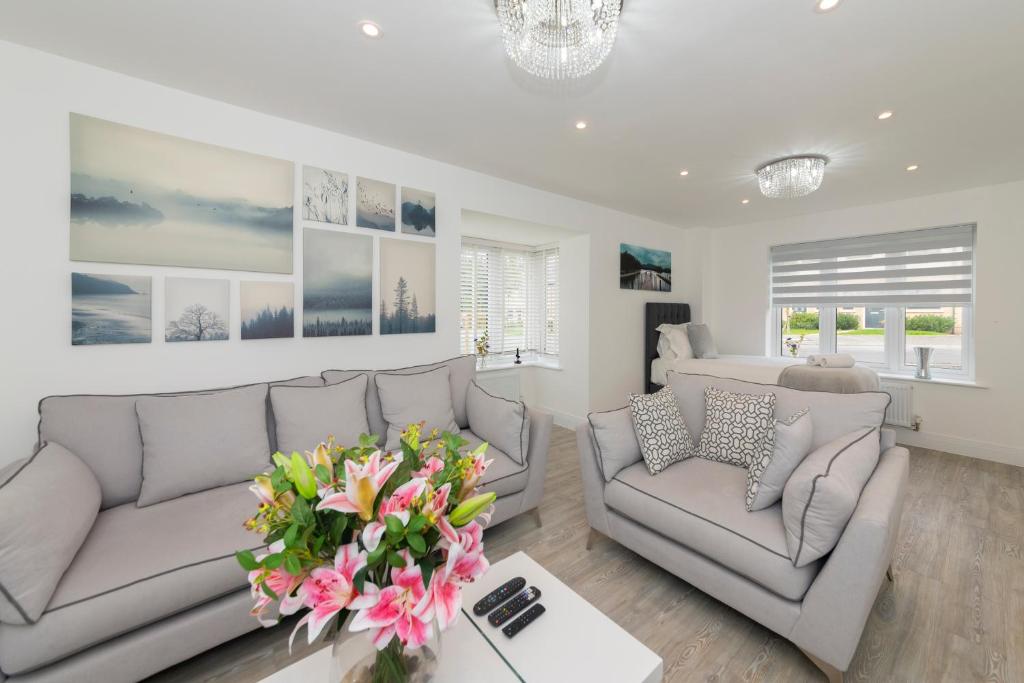 a living room with two couches and a vase of flowers at Greenfield's - New Modern 3 Bedroom Home - Johnstonen Close, Bracknell in Bracknell