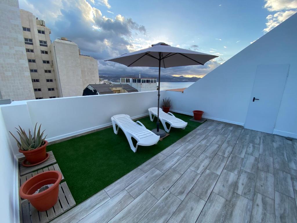 un patio con sombrilla y sillas en el techo en Holiday Home & Rooftop Lounge, en Las Palmas de Gran Canaria