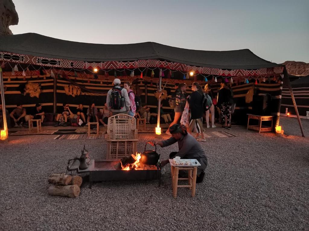un hombre está cocinando sobre un fuego en una tienda en Wadi Rum Dream Camp, en Wadi Rum