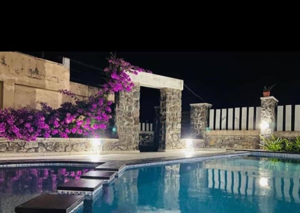 una piscina por la noche con flores púrpuras en Coral Drive Villas -Your Private Beach Destination, en Chennai