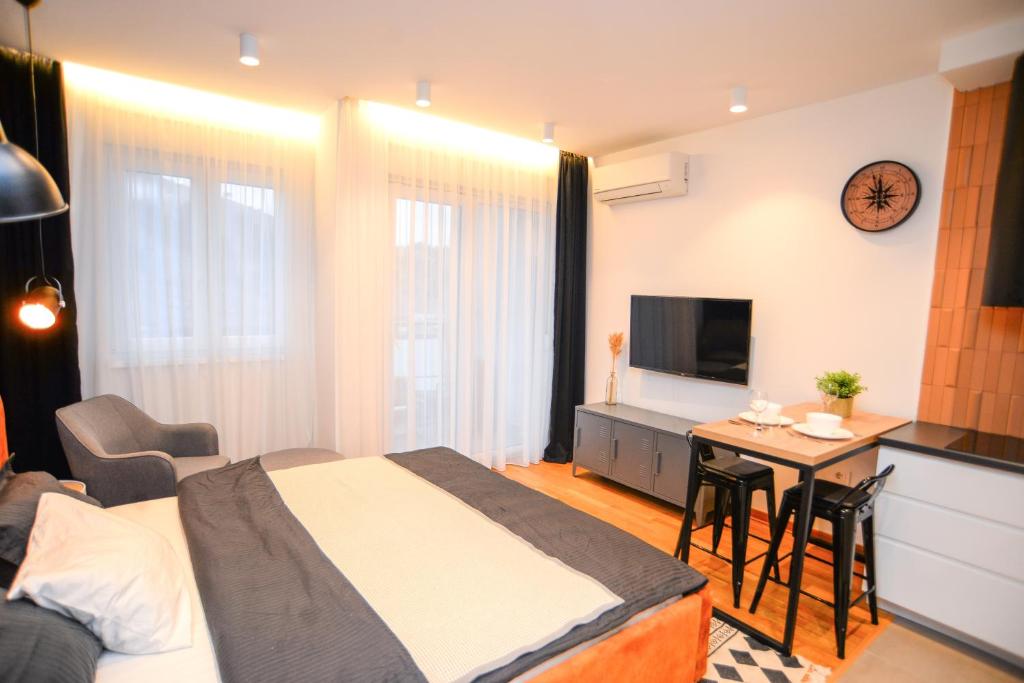 a bedroom with a bed and a table and a kitchen at Design Apartment near Gorica Park in Podgorica