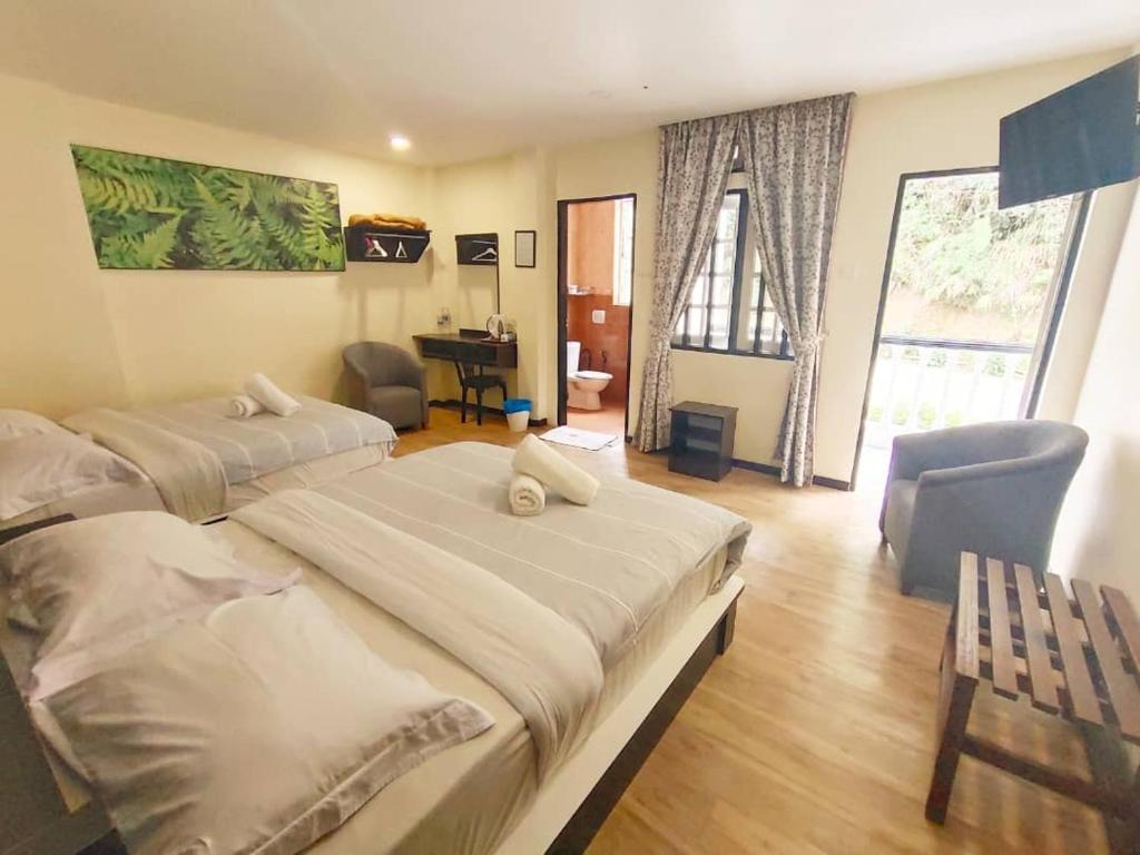 a hotel room with two beds and a desk at Hillview Inn Cameron Highlands PROMO in Tanah Rata