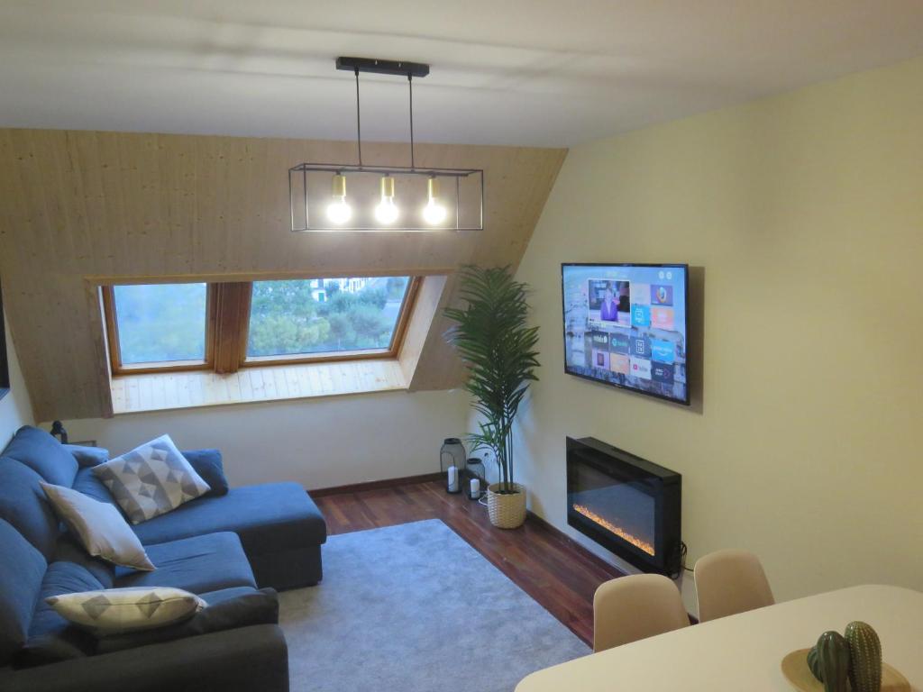uma sala de estar com um sofá azul e uma lareira em Ático Dúplex reformado con vistas a la montaña em Canfranc-Estación