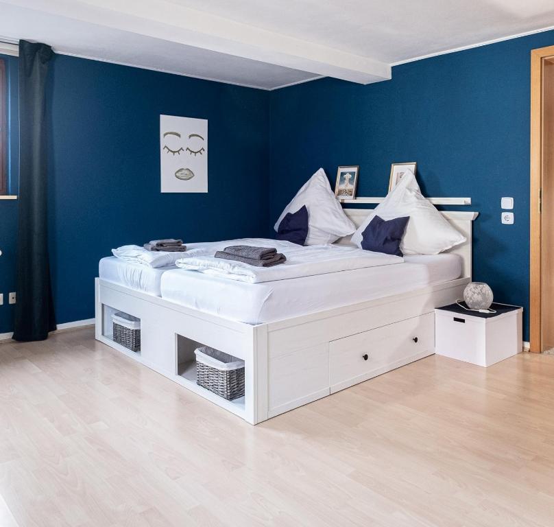 Cette chambre comprend un grand lit blanc et un mur bleu. dans l'établissement Ferienwohnung mit Kuschelflair, à Essen