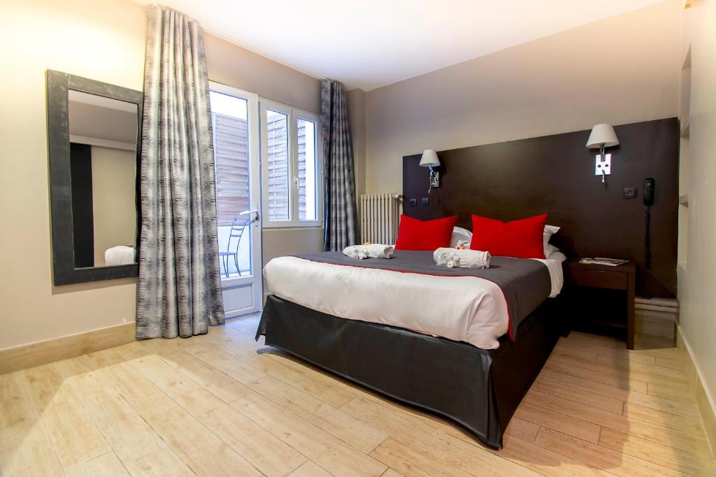 a bedroom with a large bed with red pillows at Hotel Migny Opéra Montmartre in Paris