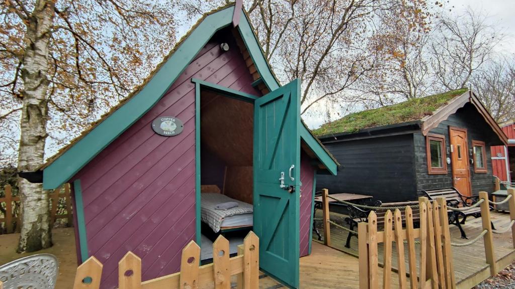 a purple and green play house with a fence at Seaways glamping, Copper Beech in Great Driffield