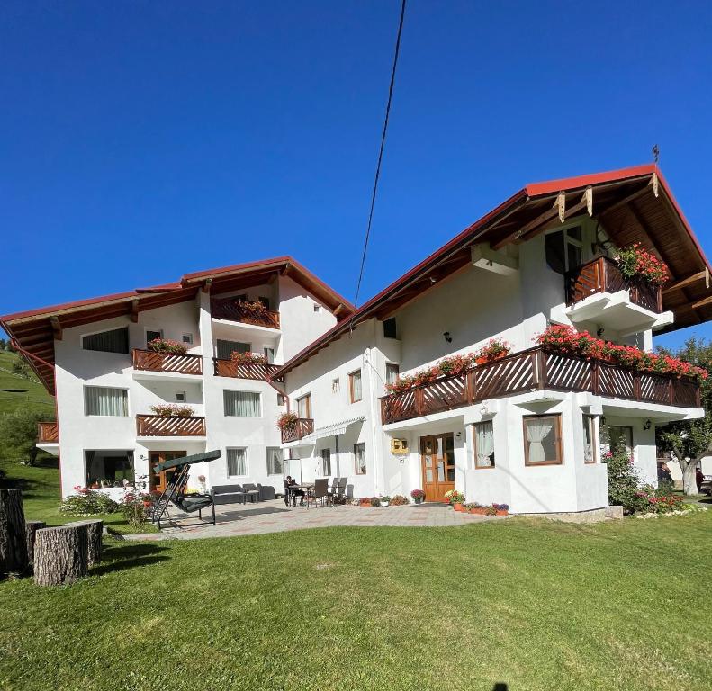 a large white building with a green yard at Pensiunea Padurea Verde in Moieciu de Sus