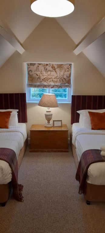 a bedroom with two beds and a lamp on a table at The Colesbourne Inn in Colesbourne