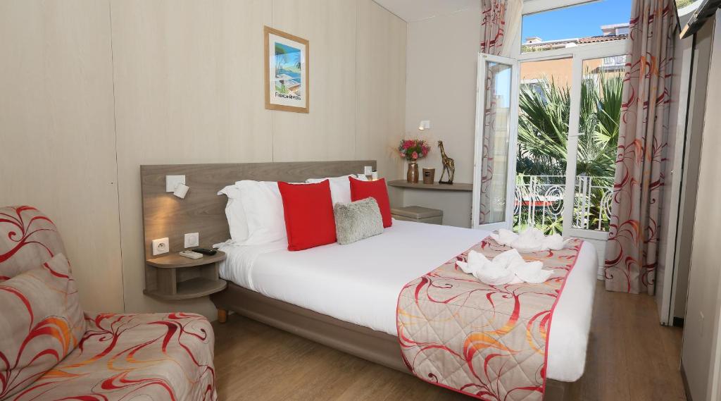 Un dormitorio con una cama grande y una ventana en Hotel Le Revest, en Sainte-Maxime