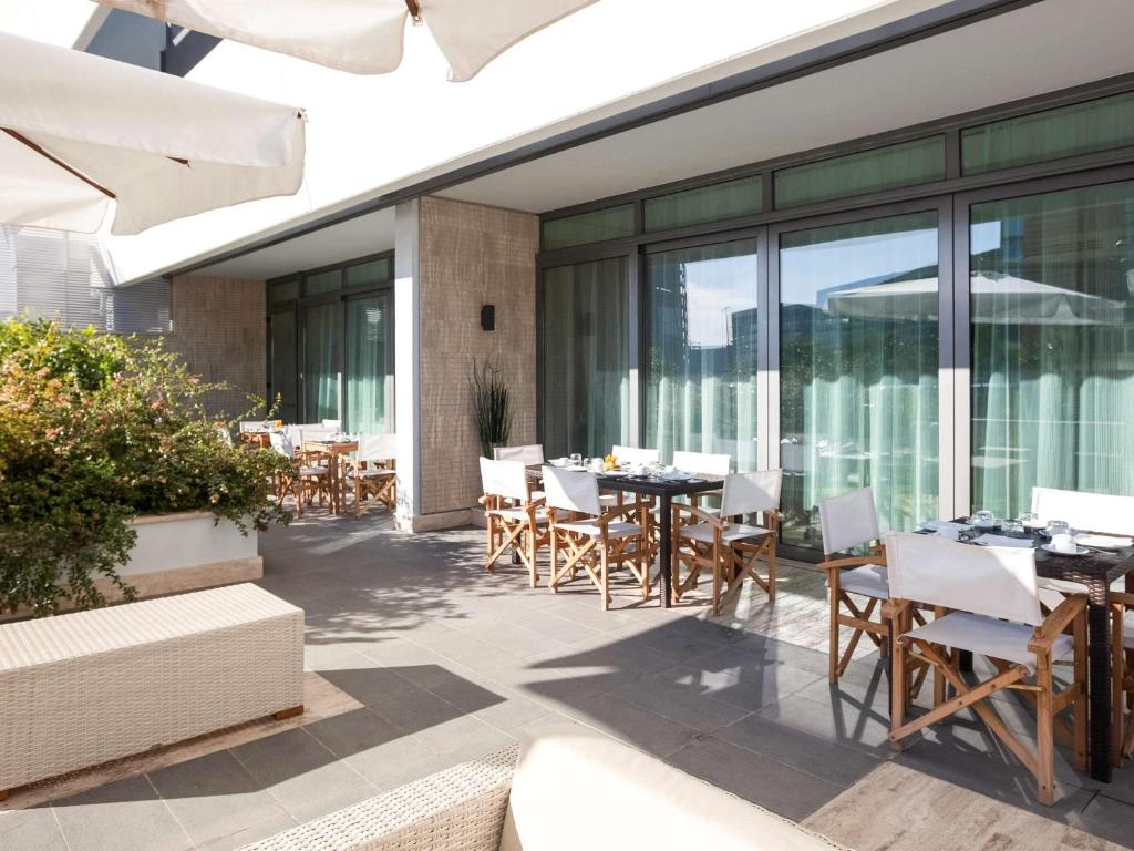 un patio esterno con tavoli, sedie e finestre di Novotel Roma Eur a Roma