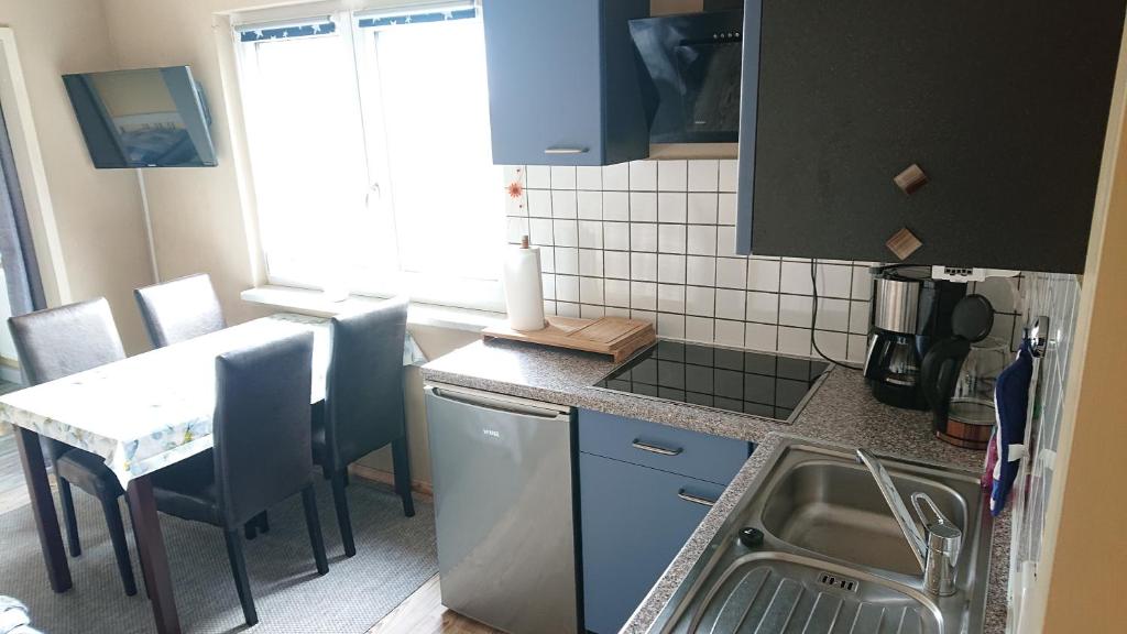 eine Küche mit einem Waschbecken und einem Tisch mit Stühlen in der Unterkunft Müller's Ferienbungalow "Zur Göltzschtalbrücke" in Greiz