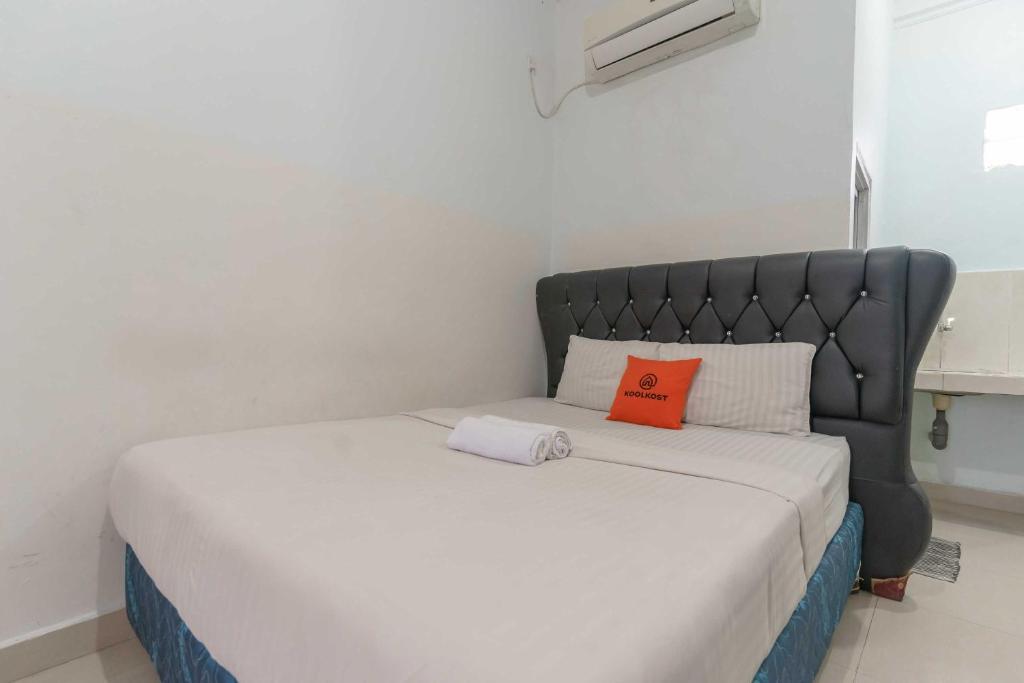 1 cama con cabecero negro y 2 almohadas en KoolKost near Palembang Icon Mall 4, en Palembang