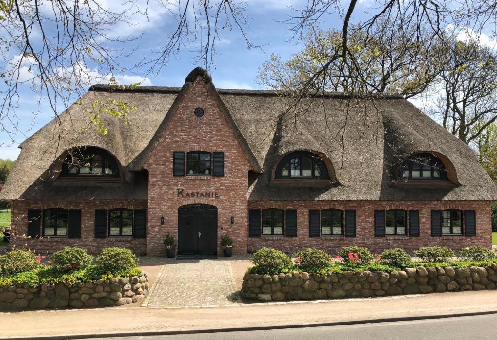 ein Backsteinhaus mit einem Strohdach in der Unterkunft Hotel und Landhaus 'Kastanie' in Hamburg