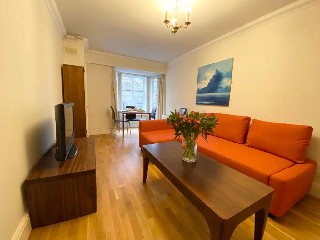 a living room with an orange couch and a table at Stylish Apartments in Victoria & Westminster in London