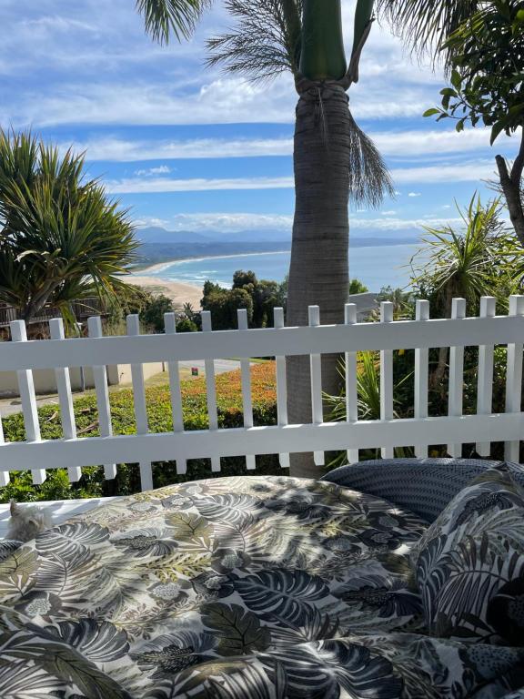a white fence with a table and a palm tree at Plett Holiday Stay with Pizza Oven and Views in Plettenberg Bay