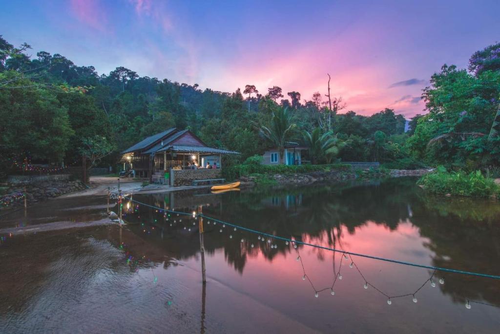 una casa sulla riva di un fiume al tramonto di เมี่ยงไม้ รีสอร์ท a Ban Khlong Khen