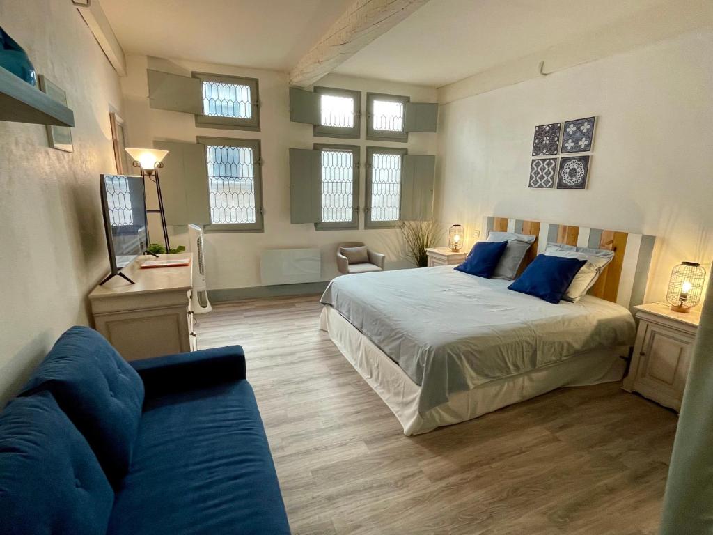 ein Schlafzimmer mit einem Bett und einer Couch und Fenstern in der Unterkunft Maison de Roche-Uzès Centre Historique L' Ucetia in Uzès