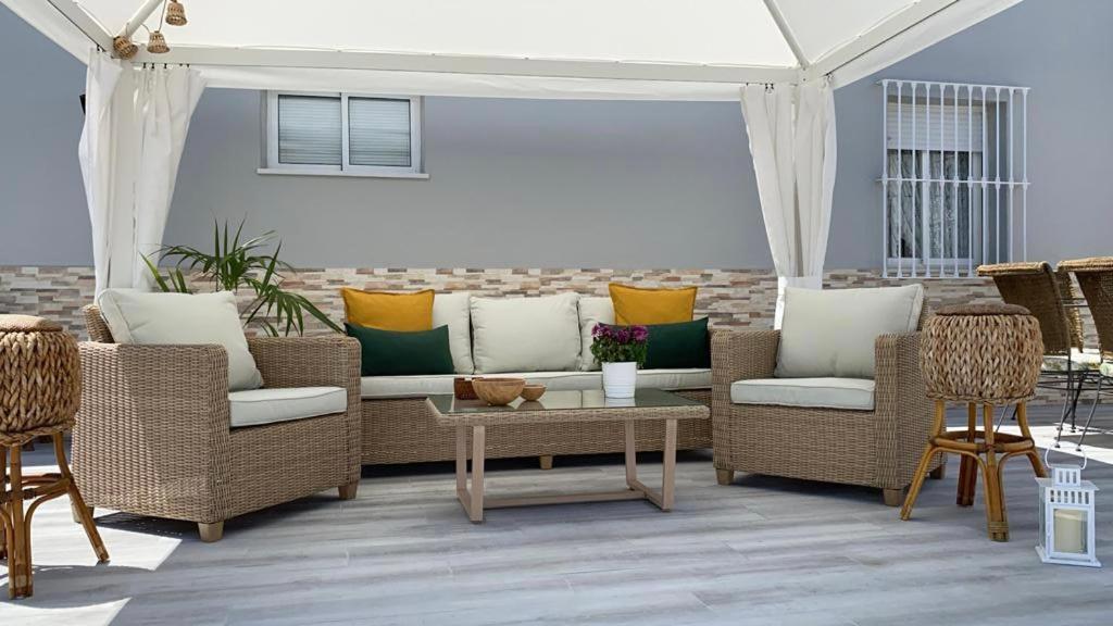 patio z wiklinowymi krzesłami, kanapą i stołem w obiekcie Casa grande con piscina w mieście Rota